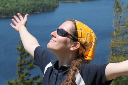 Jacqueline wearing sunglasses, arms open, looking at the sky